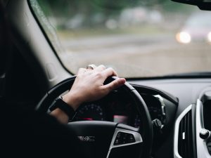 person driving with their hand on the steering wheel