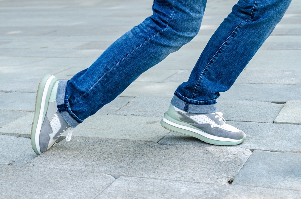 Close-up of woman's feet as she trips over sunken paver